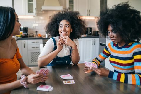 kolme tyttöä kotona pelaamassa korttia