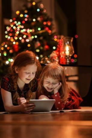 sisaret käyttävät taulutietokonetta lattialla joulun aikana