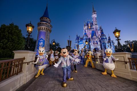 Mikki Hiiri ja ystävät yllään 50-vuotisjuhlaan hohtavan muodin päällä poseeraamassa Cinderella linnan edessä Magic Kingdom Parkissa